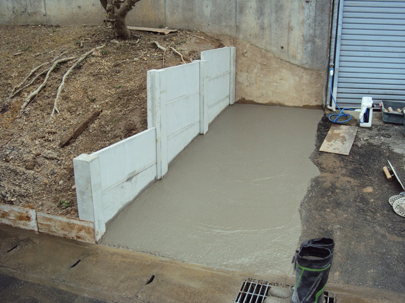 土留めには万代塀を利用しました。土間のコンクリートも打たれ、乾燥を待ちます。